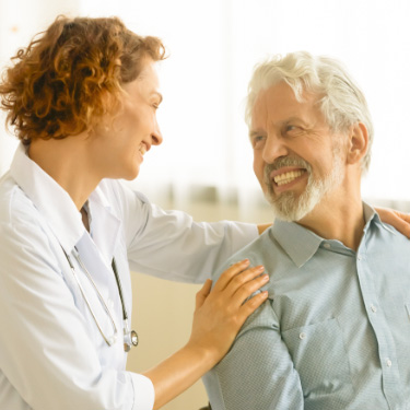 Medico e paciente sorriem em quarto de hospital.