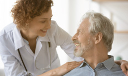 Médica sorrindo atendendo e confortando paciente em programa de Medicina preventiva.