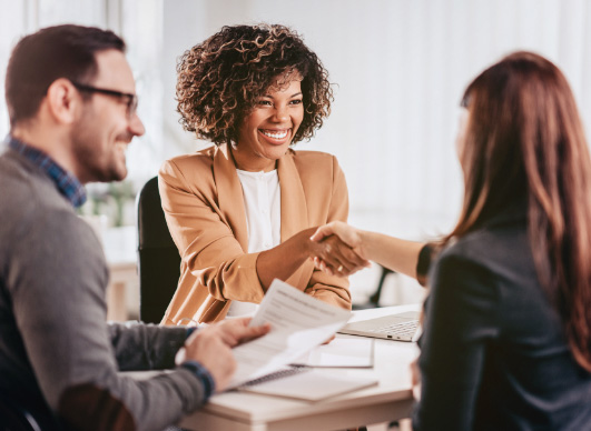 Pessoas felizes fechando negociação em mesa, atendendo a modalidades de contratação empresarial