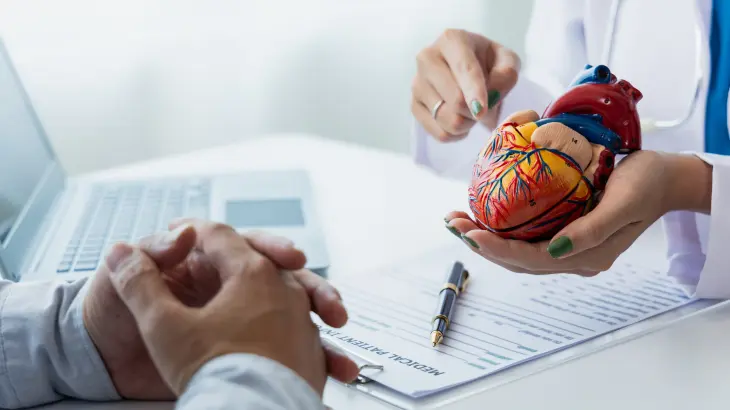 Médico com uma imagem de um coração explicando para o paciente