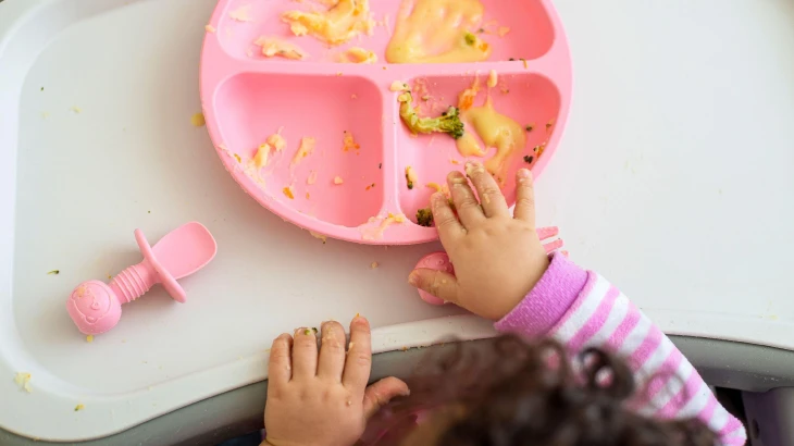 Criança com um pratinho com os alimentos todos amassados
